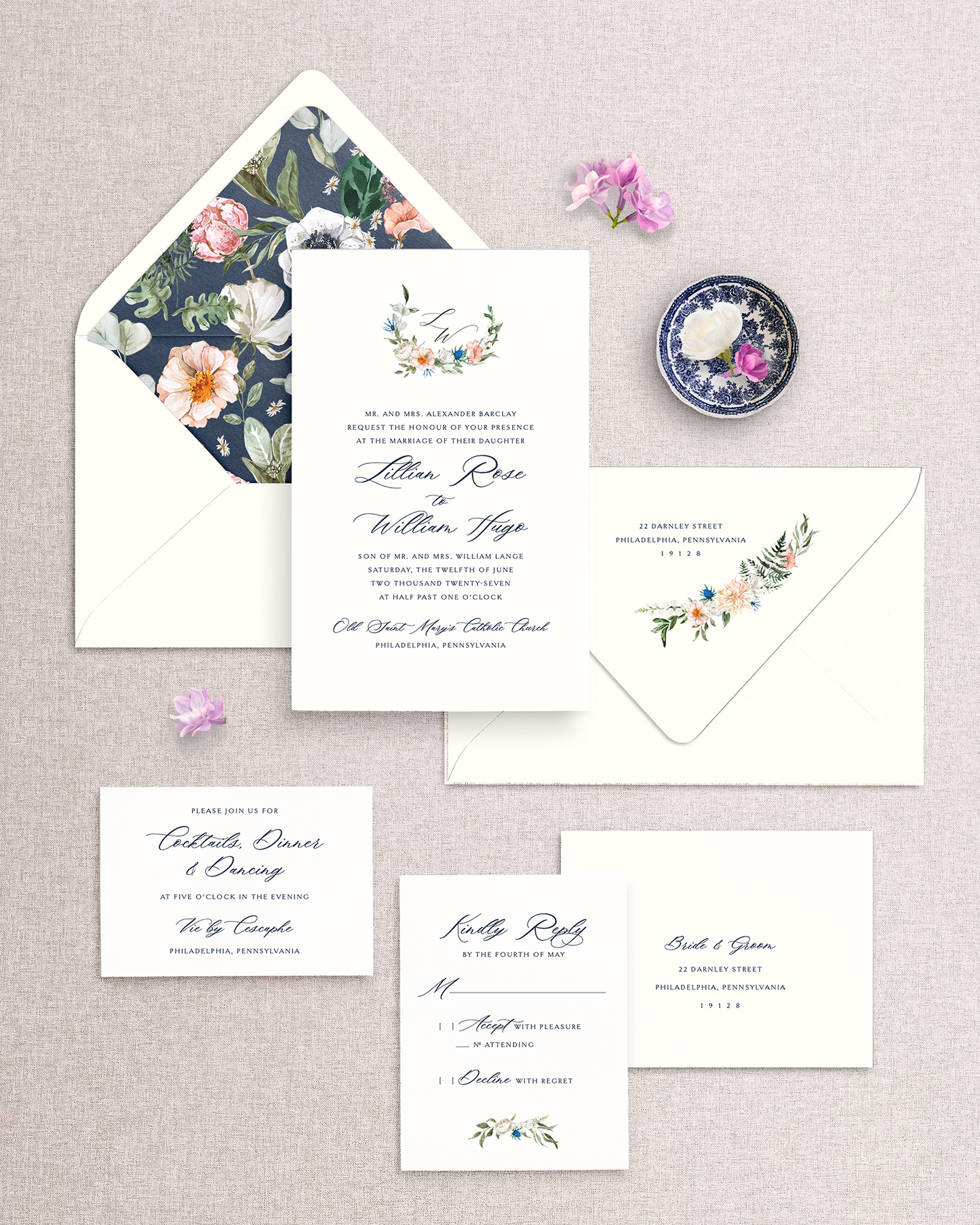 Wedding invitation set in navy ink with floral envelope liner and accent designs on a textured surface.