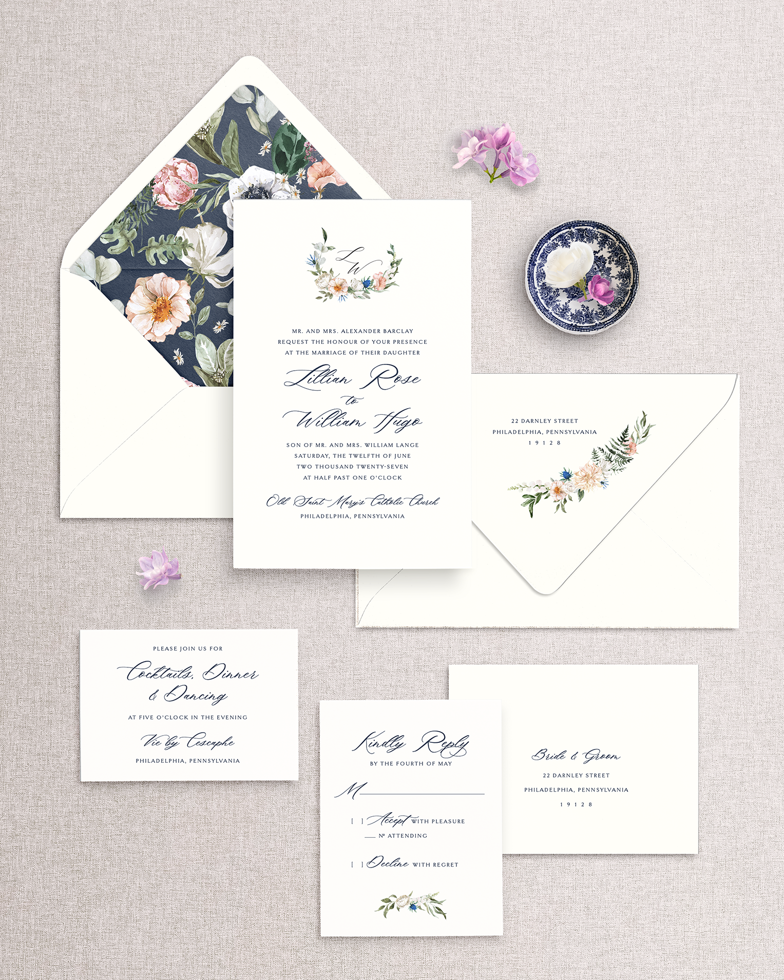 Wedding invitation set in navy ink with floral envelope liner and accent designs on a textured surface.