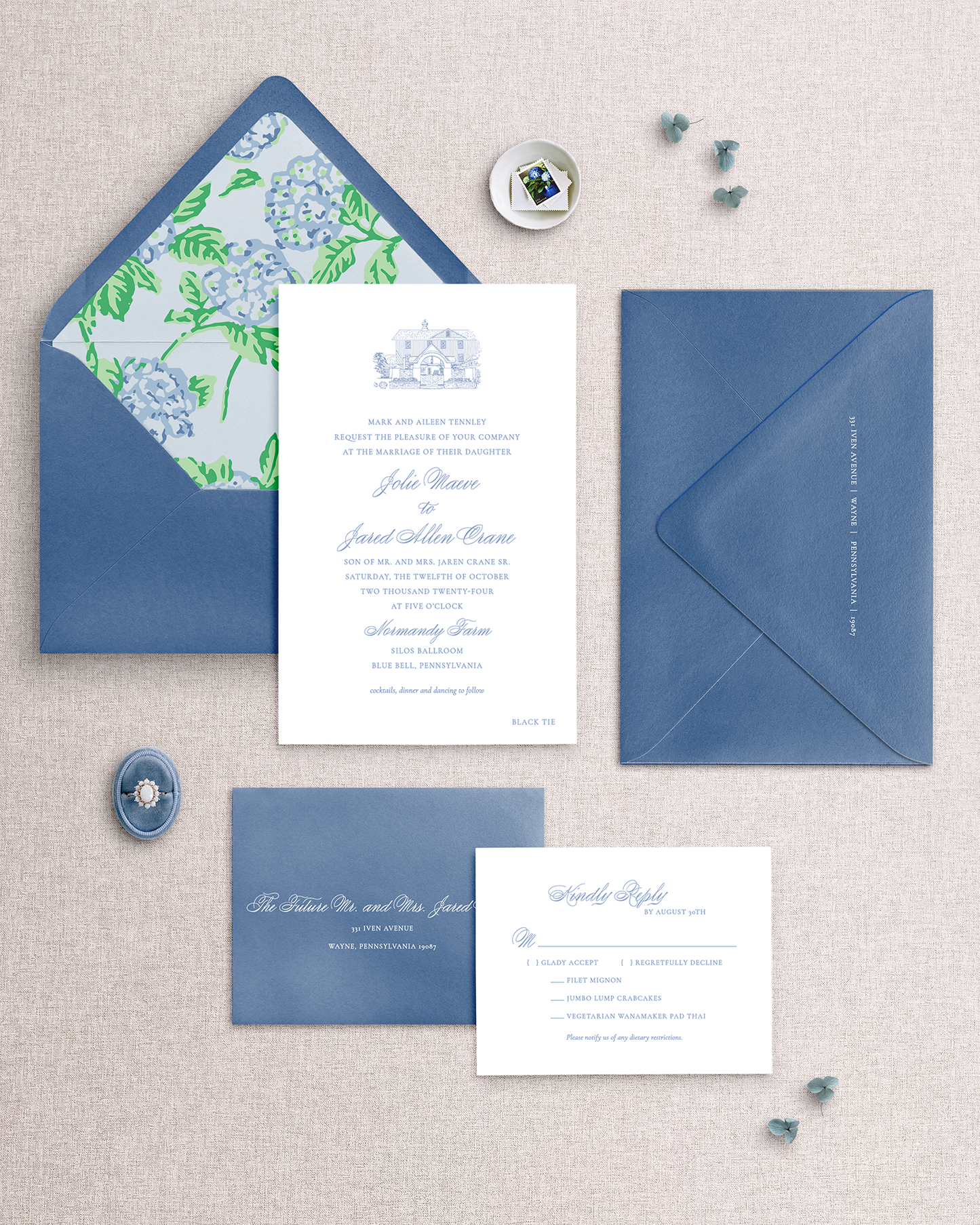 Blue and white hydrangea wedding invitation set on a textured surface