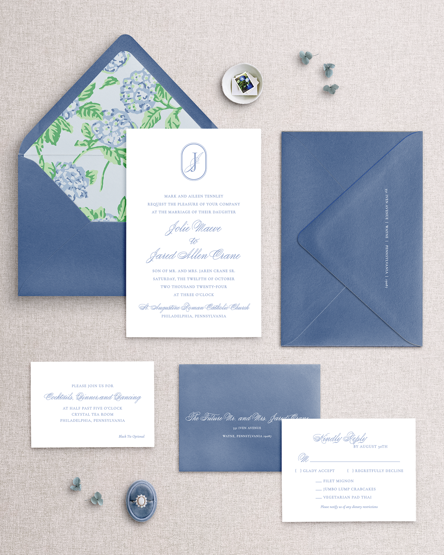 Set of blue and white hydrangea wedding invitations with matching envelopes on a textured surface.